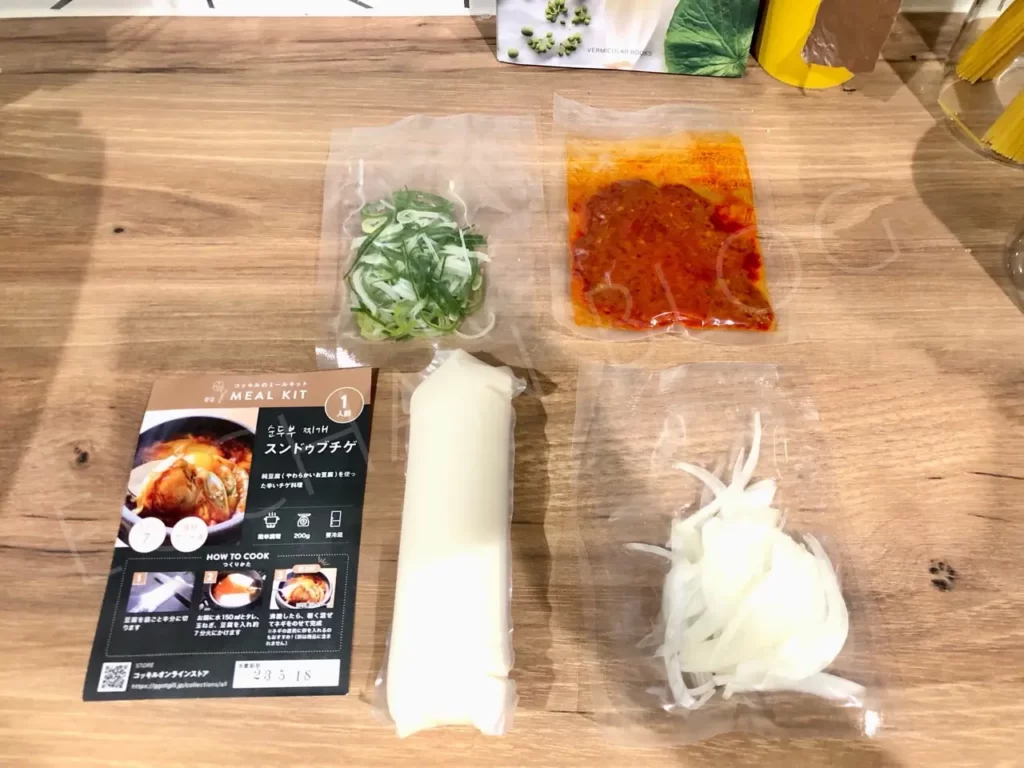 韓国料理コッキルのスンドゥブチゲミールキットに入っている材料の一覧。豆腐、スライス玉ねぎ、切ってあるネギ、特製タレが入っている。